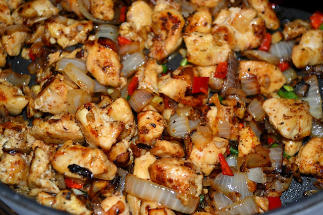 chicken, peppers, and onions cooking in a skillet 