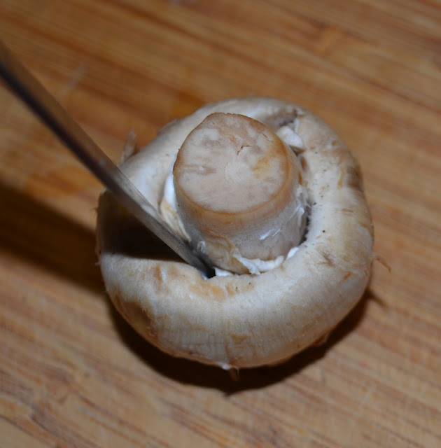 cutting out the inside of a mushroom with a knife to stuff it with cheese 