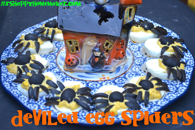 Deviled Egg Spiders on an egg plate surrounding a ceramic mini haunted house decoration 