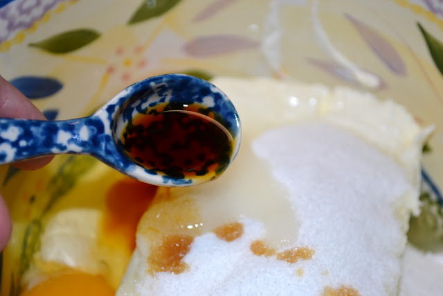 a small teaspoon of vanilla extract being poured into a bowl 