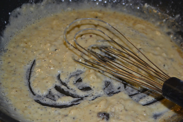 the sausage gravy roux being whisked in a skillet 