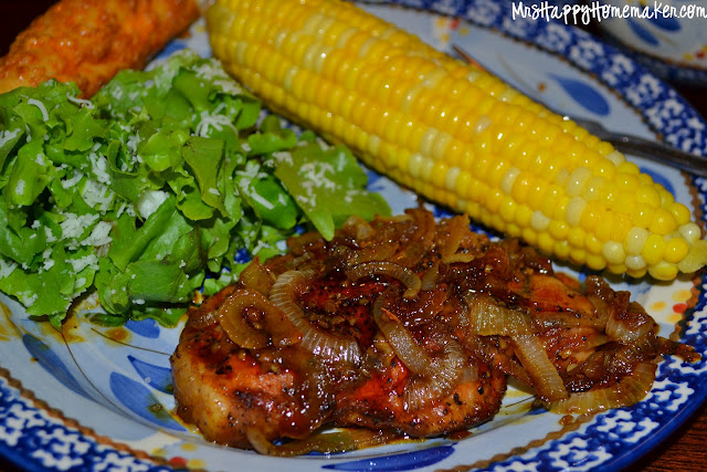sweet and savory pork chops and onions on a plate with salad and corn 