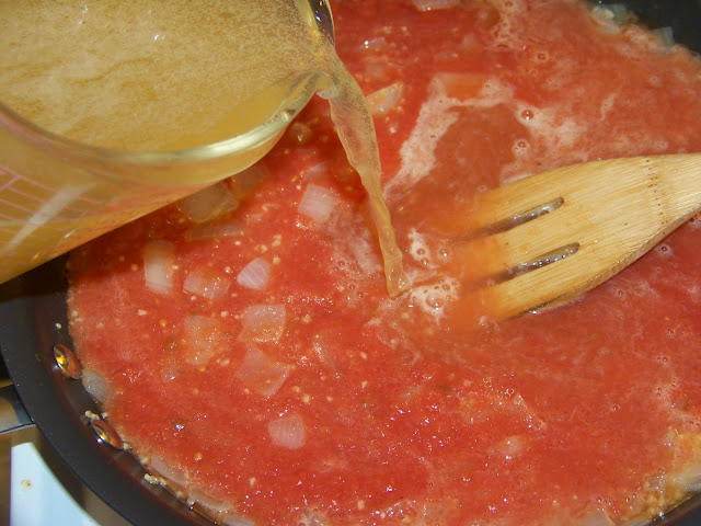 pouring chicken broth into red sauce 