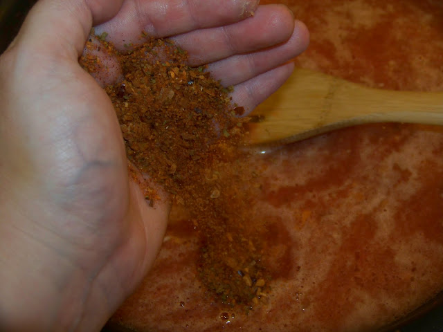 Pouring seasonings into red sauce 