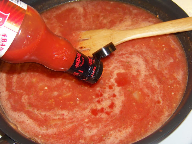 Pouring hot sauce into red sauce in a pot